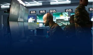 Military personnel monitoring multiple screens in a defence command and control room