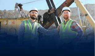 Two male workers in safety gear shaking hands at an open-pit mining site