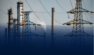 Industrial power plant with tall chimneys and electricity transmission towers at dusk