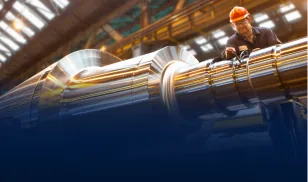 Worker in orange helmet inspecting large steel cylindrical components in a factory
