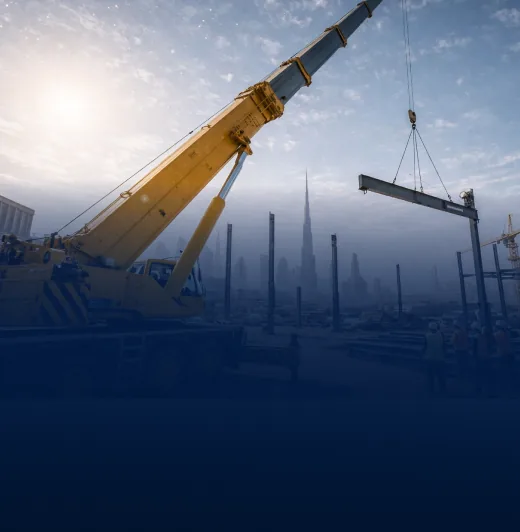 Yellow mobile crane lifting a steel beam at a construction site with city skyline