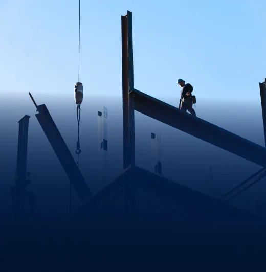 Silhouette of a worker walking on steel beams of a self-standing structure at dusk